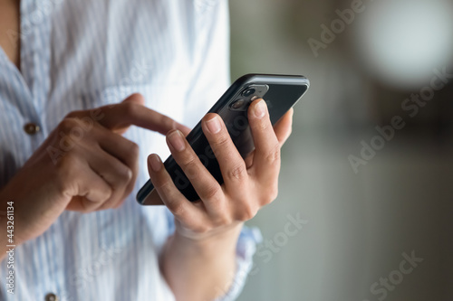 Foto Close up cropped of woman holding smartphone in hand, typing on screen writing m