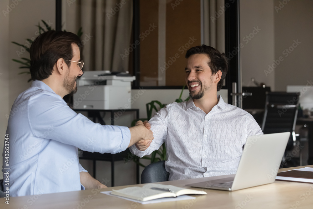 Smiling hr manager shaking successful candidate hand, greeting at job interview or congratulating with hiring, advisor businessman making great deal with customer or business partner at meeting