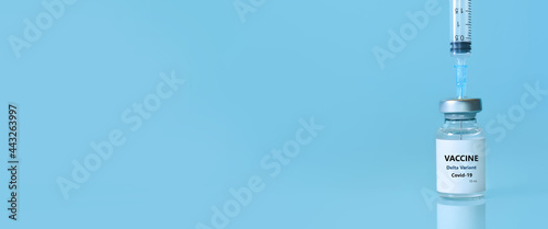 Vaccine in a bottle with a syringe on a blue background.The concept of medicine, healthcare and science.Coronavirus vaccine.Copy space for text.Banner © syhin_stas