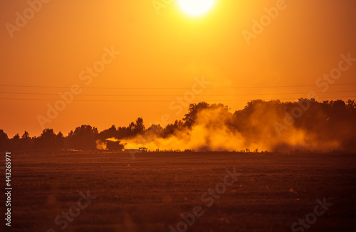 A harvester working on the field during the sunset hours in summer. Summertime scenery of Northern Europe.
