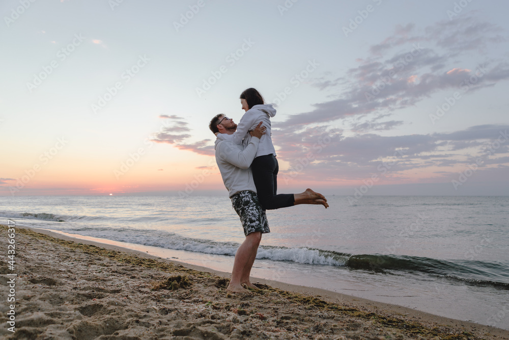 couple hugging look at sunset above sea