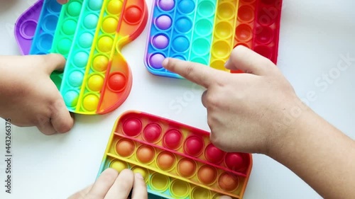 Children hands playing multicolored pop-it toy. Anti Stress Sensory Toy, Trend 2021.