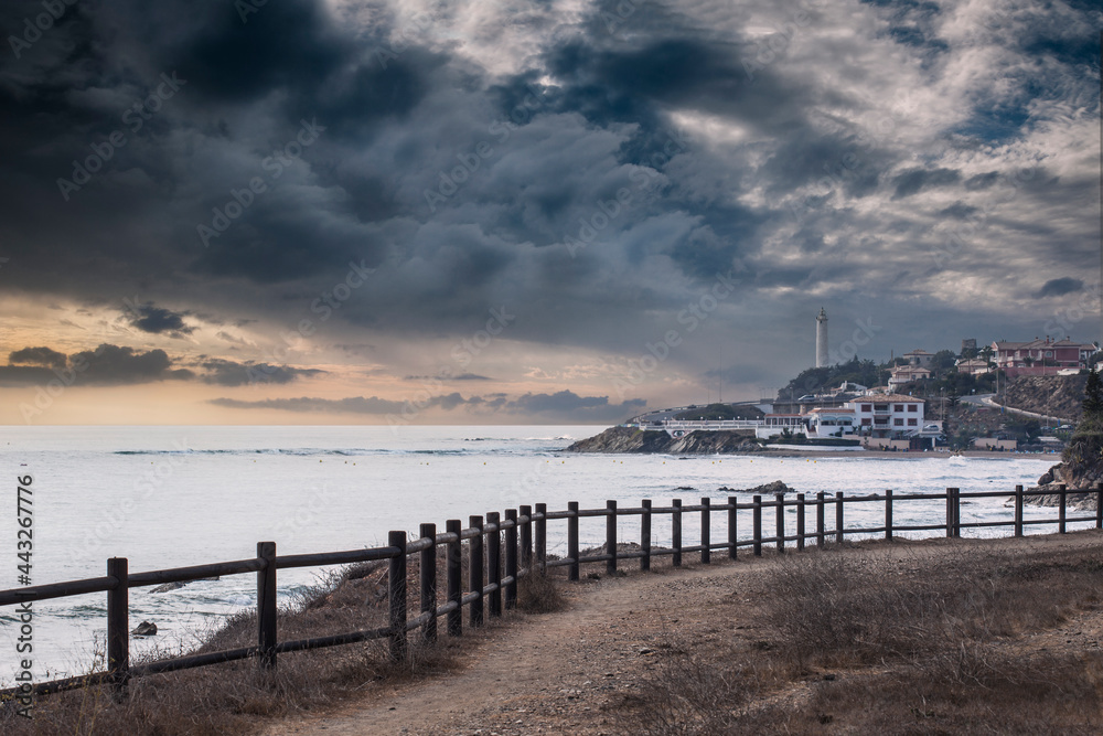 Obraz premium Imagen del faro de Calaburras en Mijas costa Málaga , España.Podemos ver el faro una valla de madera el mar y un día muy nublado.