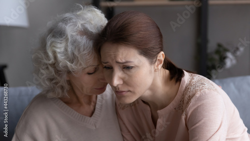 Stressed depressed young adult female daughter share life love health problems with supportive mature mom. Understanding senior granny hug cuddle suffering grandkid touch head show empathy try to help