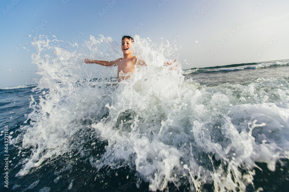 Happy child playing in the sea. Kid having fun outdoors. Summer vacation and healthy lifestyle concept. Selective focus