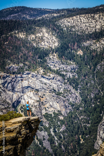 A woman in trekking outfit is standing on Taft Point at Yosemite National Park