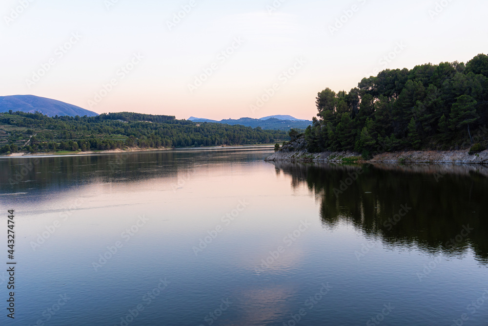Beniarres's dam at dusk, with some reflections on the water, with a clear sky.