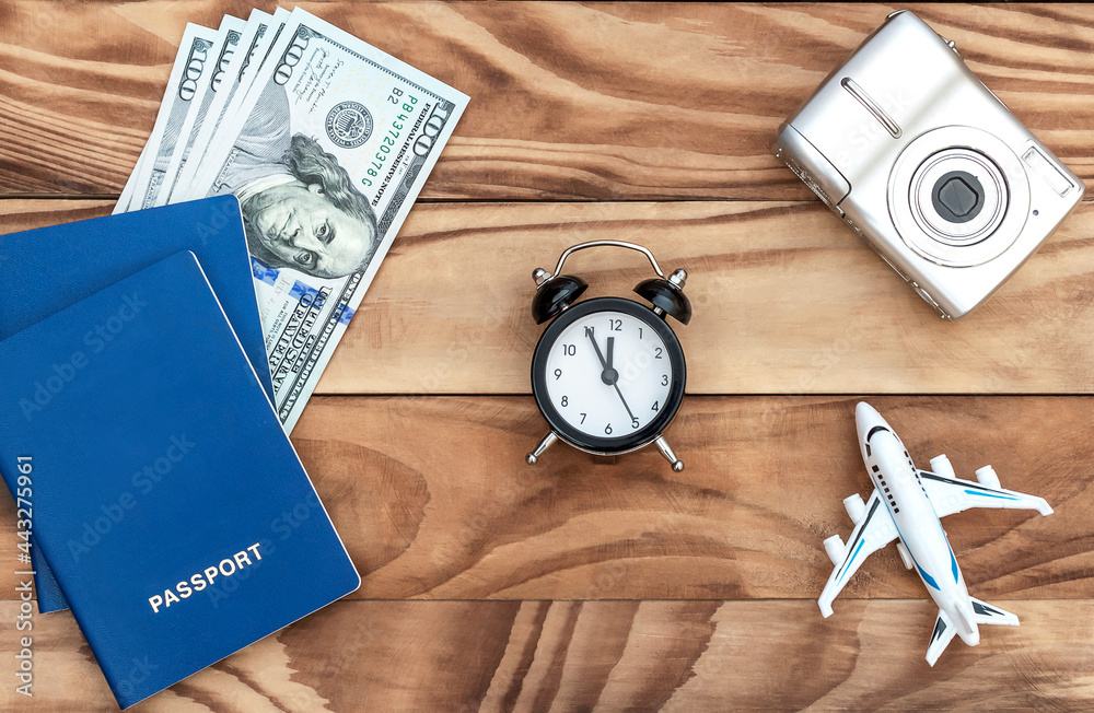 Alarm clock with airplane toy, camera and passports with money on wooden background. Time to vacation trip. Alarm clock with airplane toy, camera and passports with money on wooden background. Time to vacation trip.
