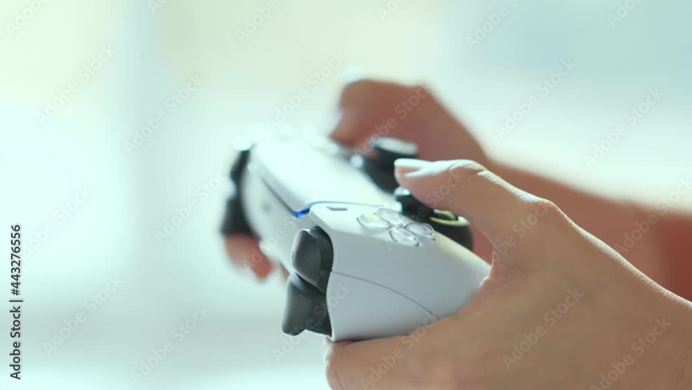 Closeup - Hands holding controller presses buttons on game joystick and play TV game.