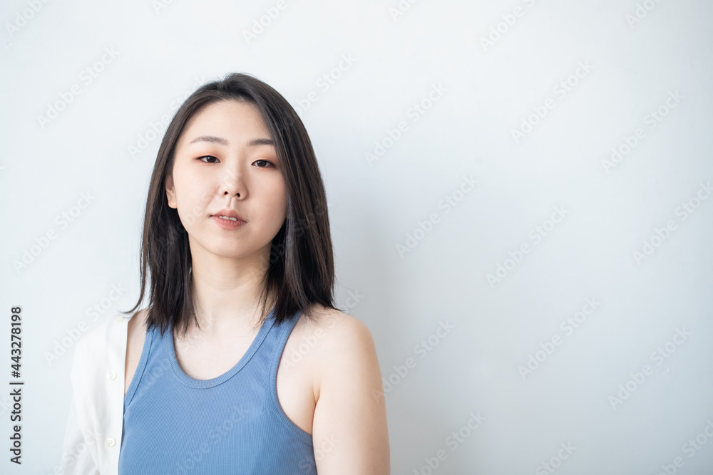 Korean Asian young woman in a stylish light-colored fashion shirt on a white background in the studio. Portrait. Lifestyle. The natural beauty of a girl Korean Asian young woman in a stylish light-colored fashion shirt on a white background in the studio. Portrait. Lifestyle. The natural beauty of a girl