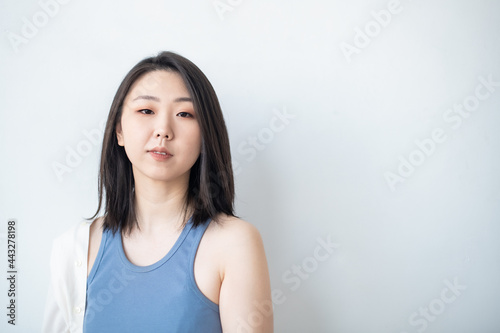 Korean Asian young woman in a stylish light-colored fashion shirt on a white background in the studio. Portrait. Lifestyle. The natural beauty of a girl