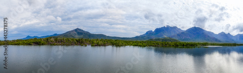 Panorama overlooking the green mangrove forests against the backdrop of distant blue mountains.