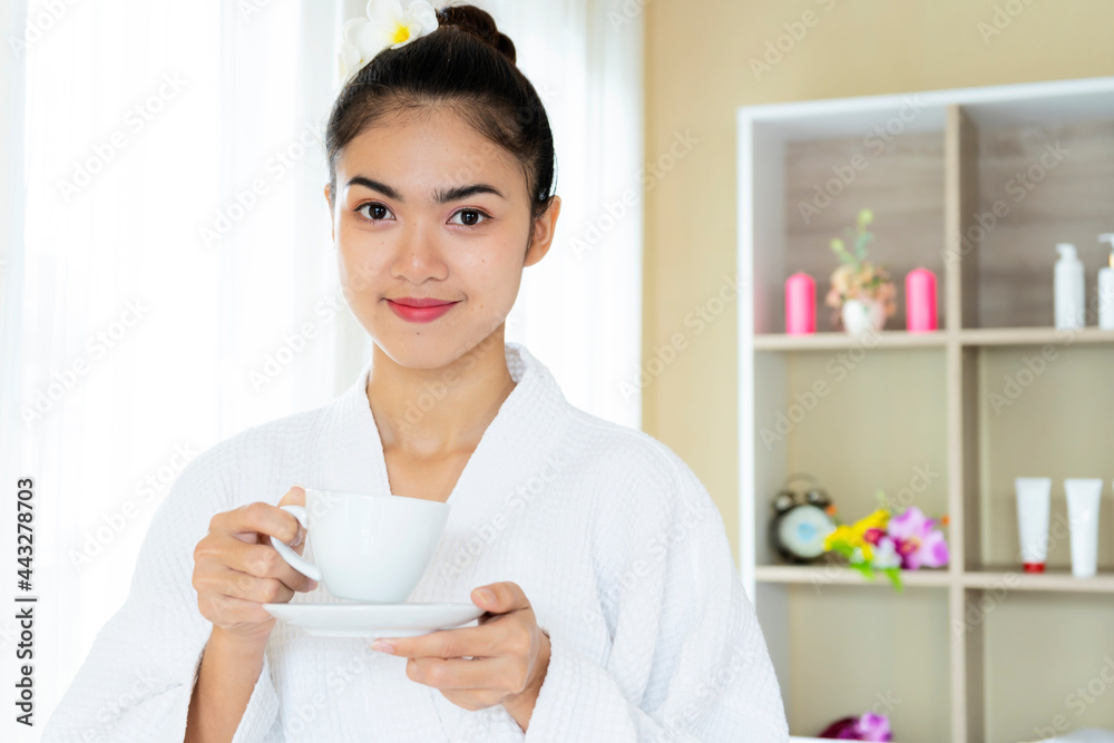 Woman in bath robe drinking tea in wellness spa