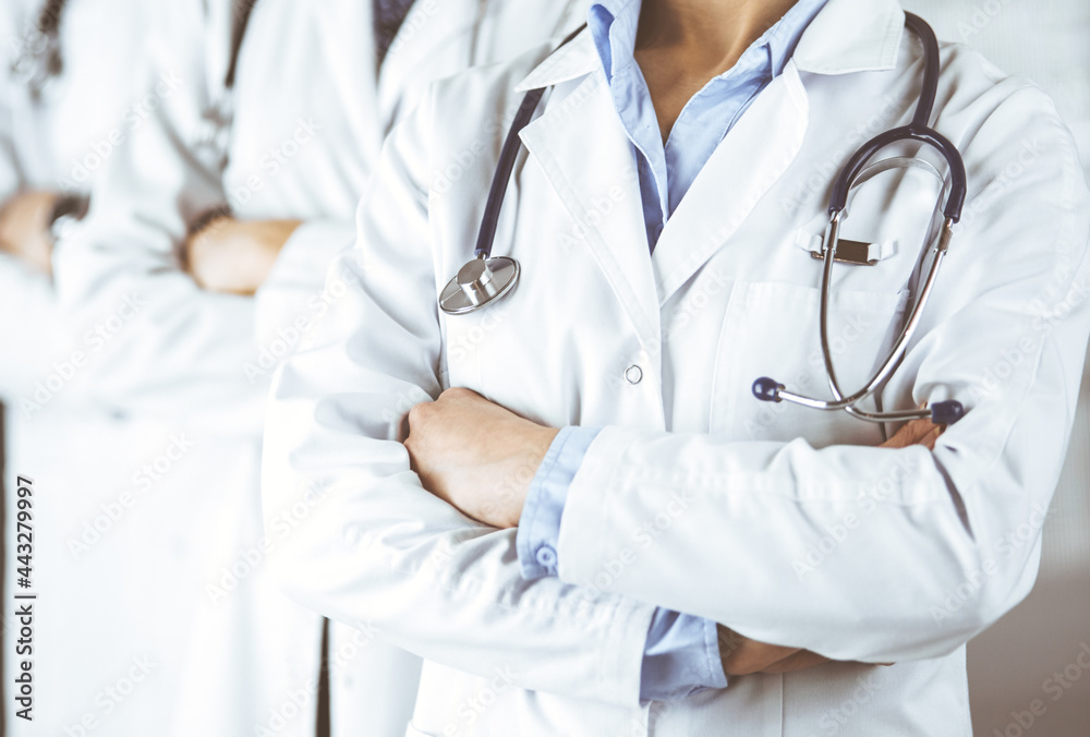 Group of modern doctors standing as a team with arms crossed in hospital office and ready to help patients. Medical help, insurance in health care, best disease treatment and medicine concept Group of modern doctors standing as a team with arms crossed in hospital office and ready to help patients. Medical help, insurance in health care, best disease treatment and medicine concept