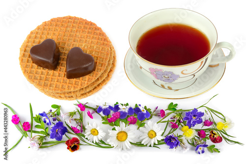 Cup of tea, waffles, chocolate candies and floral ornament isolated on white . Collage