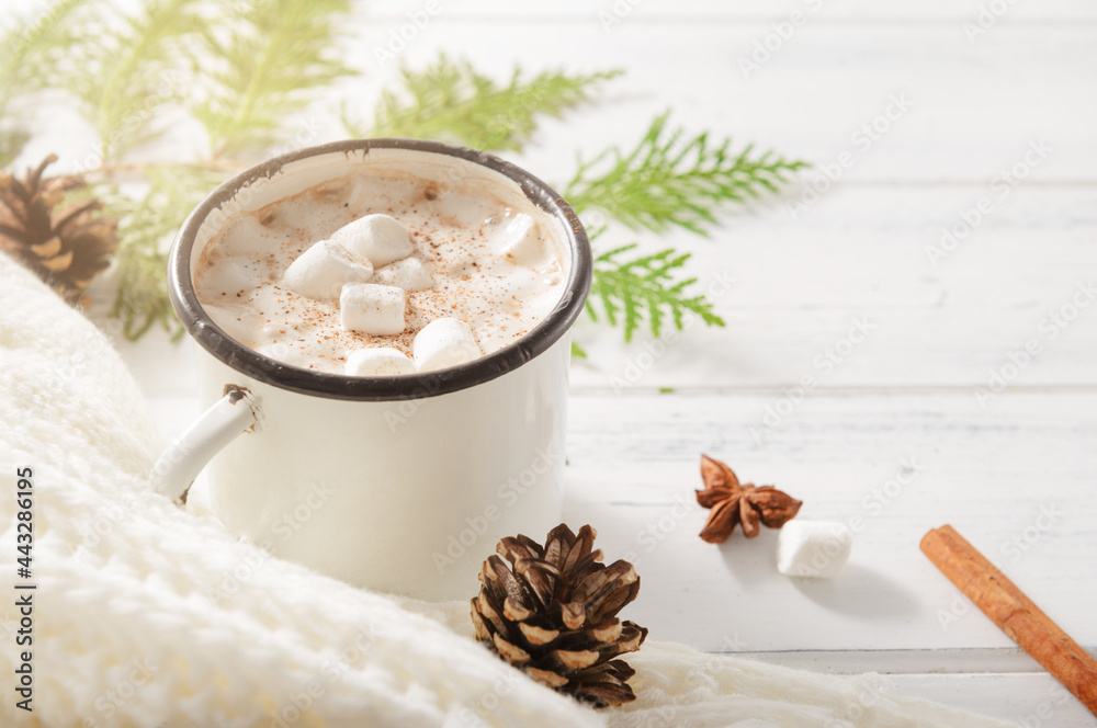 chocolate mug with marshmallows, cone, cinnamon sticks, white sweater, fir branches on a white wooden background, place for the inscription chocolate mug with marshmallows, cone, cinnamon sticks, white sweater, fir branches on a white wooden background, place for the inscription