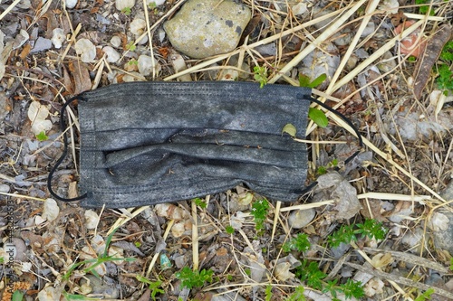 Flu face mask discarded and lying on the ground in a forest, park or other outdoor location. 