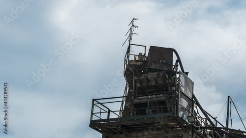 Clouds drift behind a tower of an abandoned factory, timelapse shot