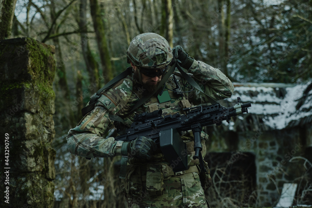 Portrait of airsoft player in professional equipment with machine gun in the forest. Soldier with weapons at war