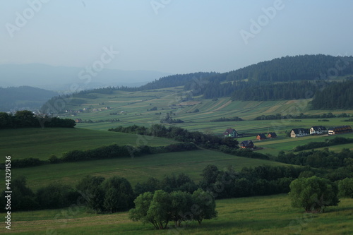 Landscape with houses in the valley between green hills