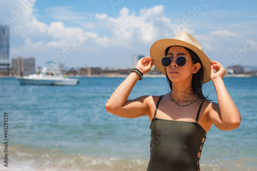 young latin woman standing on the beach wearing a summer hat © David