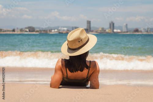 young latin womanat the beach wearing a summer hat 