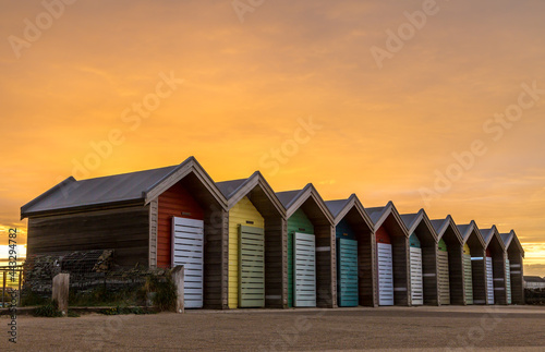 The vibrant and colorful beach huts by the promenade overlooking Blyth beach with a lovely sunset in Northumberland, England
