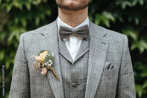 Groom wearing a bowtie and grey suit close up