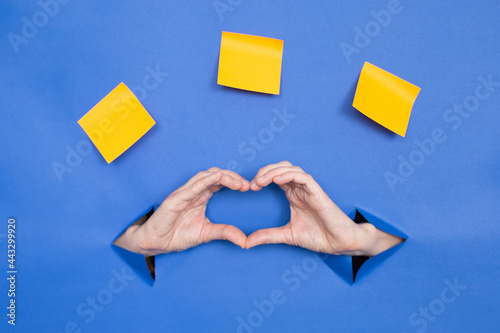 Women's hands in the shape of a heart on a blue background.