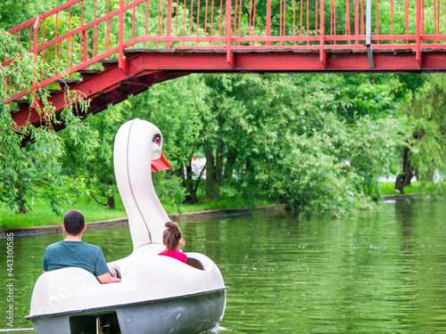 Father and daughter on a pedal boat in shape of a swan in Alexandru Ioan Cuza Titan Park enjoying a nice summer day photo