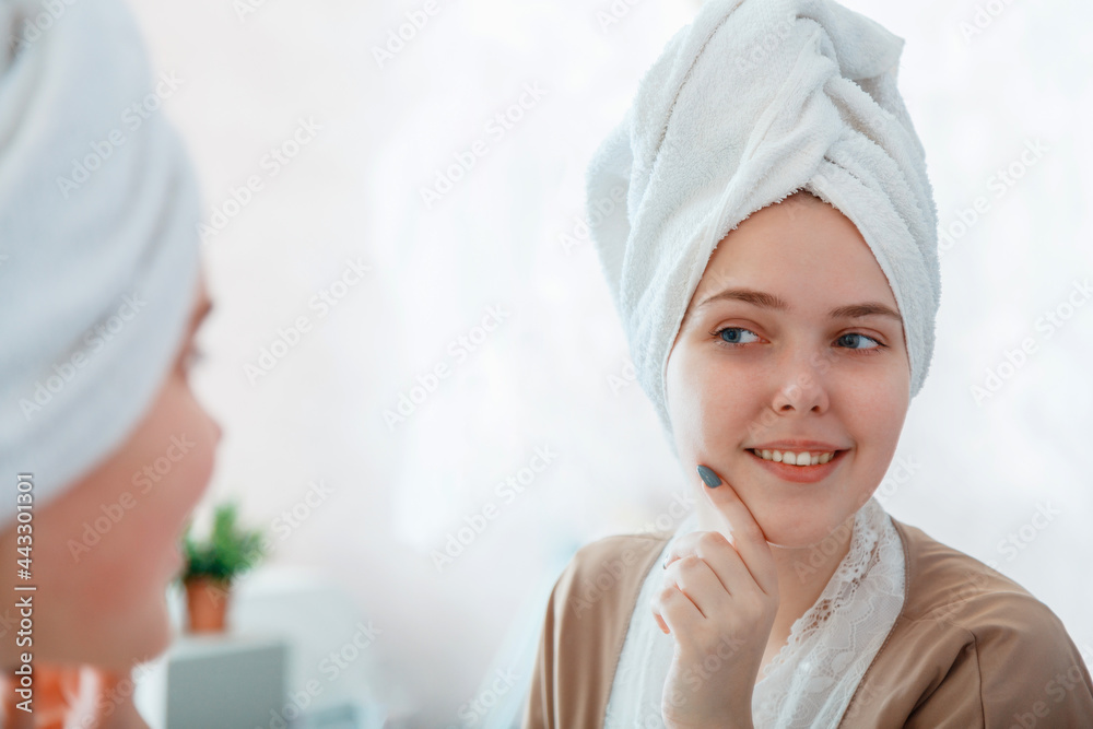Self Care as part of morning bathroom routine. Portrait of smiling young woman with perfect skin in mirror reflection after taking shower before makeup with towel on head. Self Care as part of morning bathroom routine. Portrait of smiling young woman with perfect skin in mirror reflection after taking shower before makeup with towel on head.