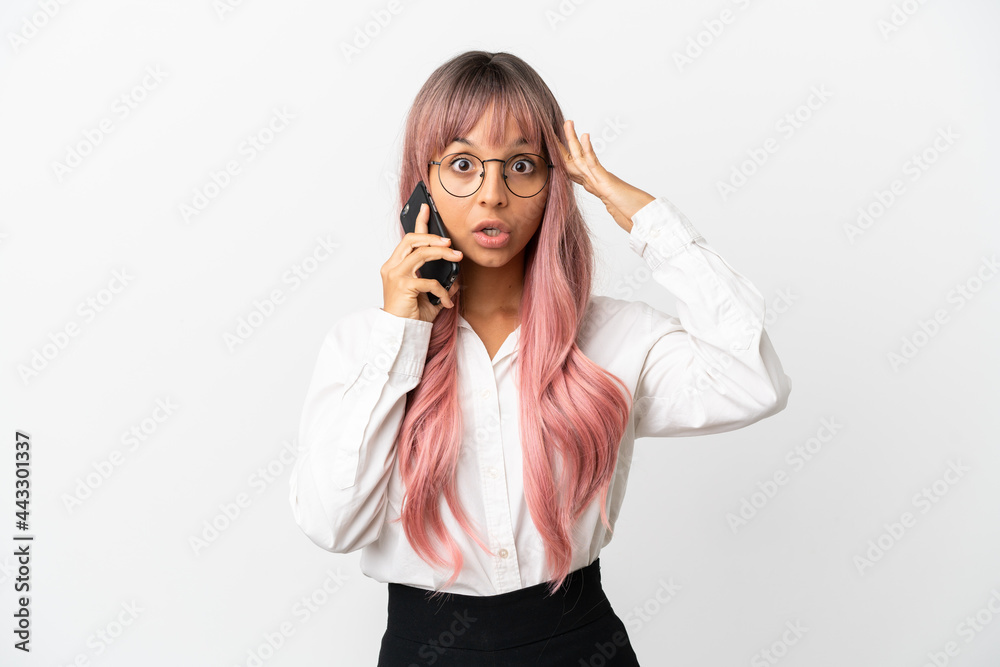 Young business mixed race woman with pink hair holding a mobile isolated on pink background with surprise expression Young business mixed race woman with pink hair holding a mobile isolated on pink background with surprise expression