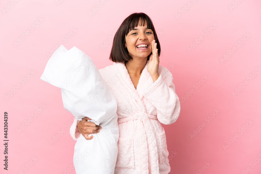 Young mixed race pregnant woman isolated on pink background in pajamas and shouting with mouth wide open