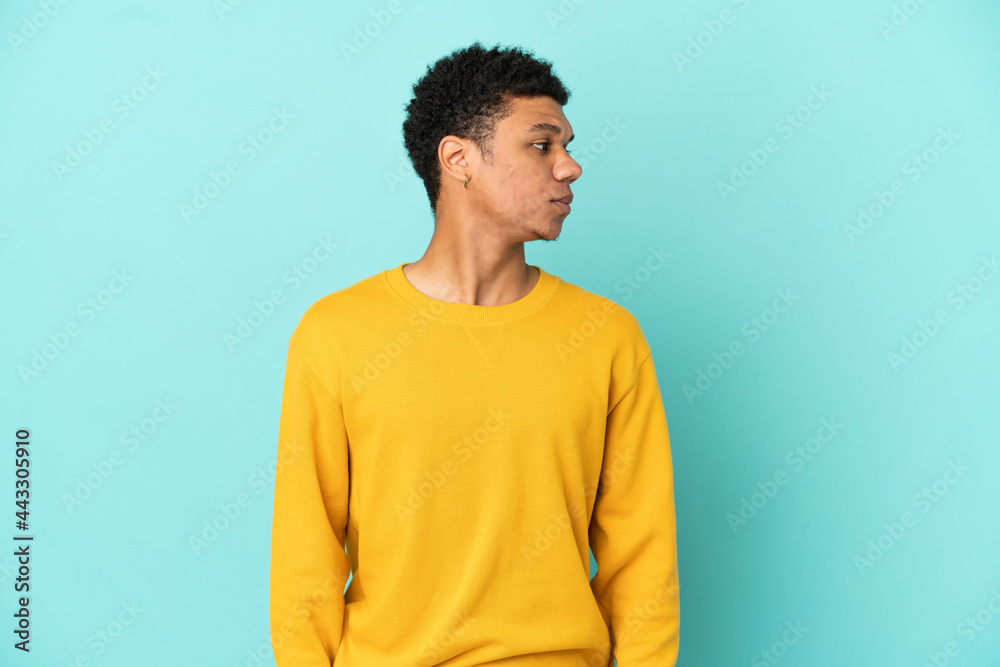 Young African American man isolated on blue background looking to the side Young African American man isolated on blue background looking to the side
