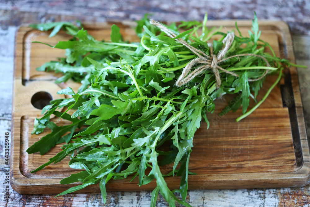 Selective focus. Fresh juicy arugula bunch on a wooden board. Selective focus. Fresh juicy arugula bunch on a wooden board.
