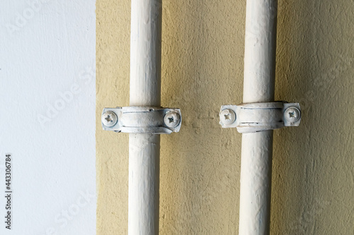 Two pipes are tied to the yellow wall.