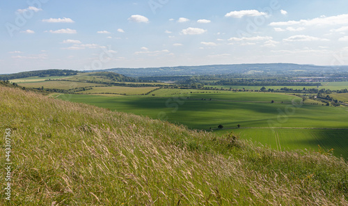British spring landscape with hills, meadows and farms under blue cloudy sky.