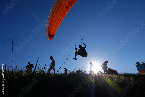 Brazil, Sao-Paulo, Guaruja 09 February 2019: Paraglider is flying in the sky above the mountains and people looking at him.The main area for paragliding photo