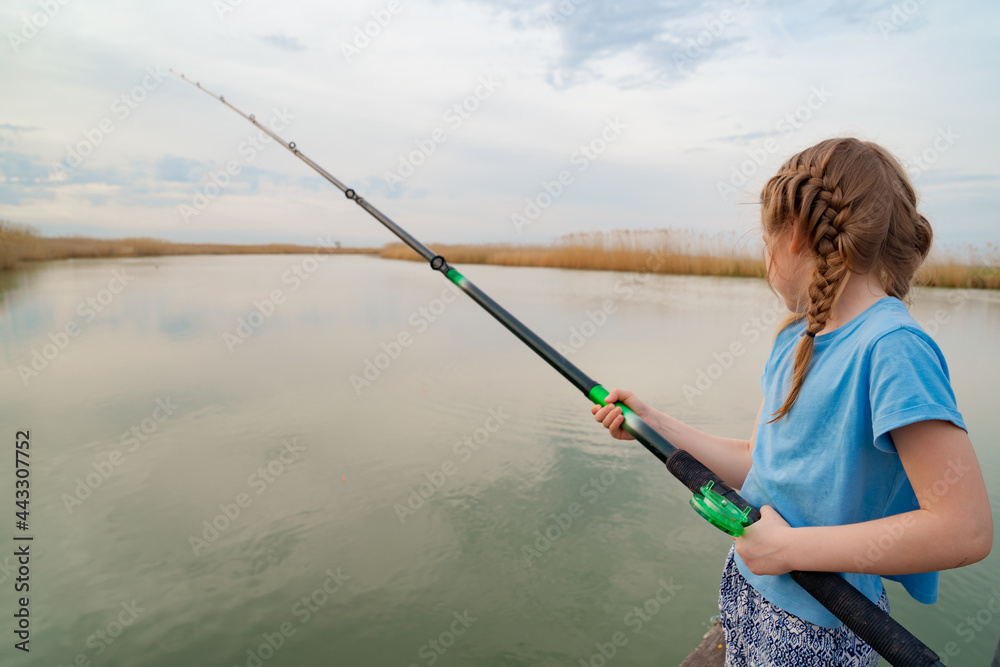 rear view. little girl on a river with fishing rod. rear view. little girl on a river with fishing rod.