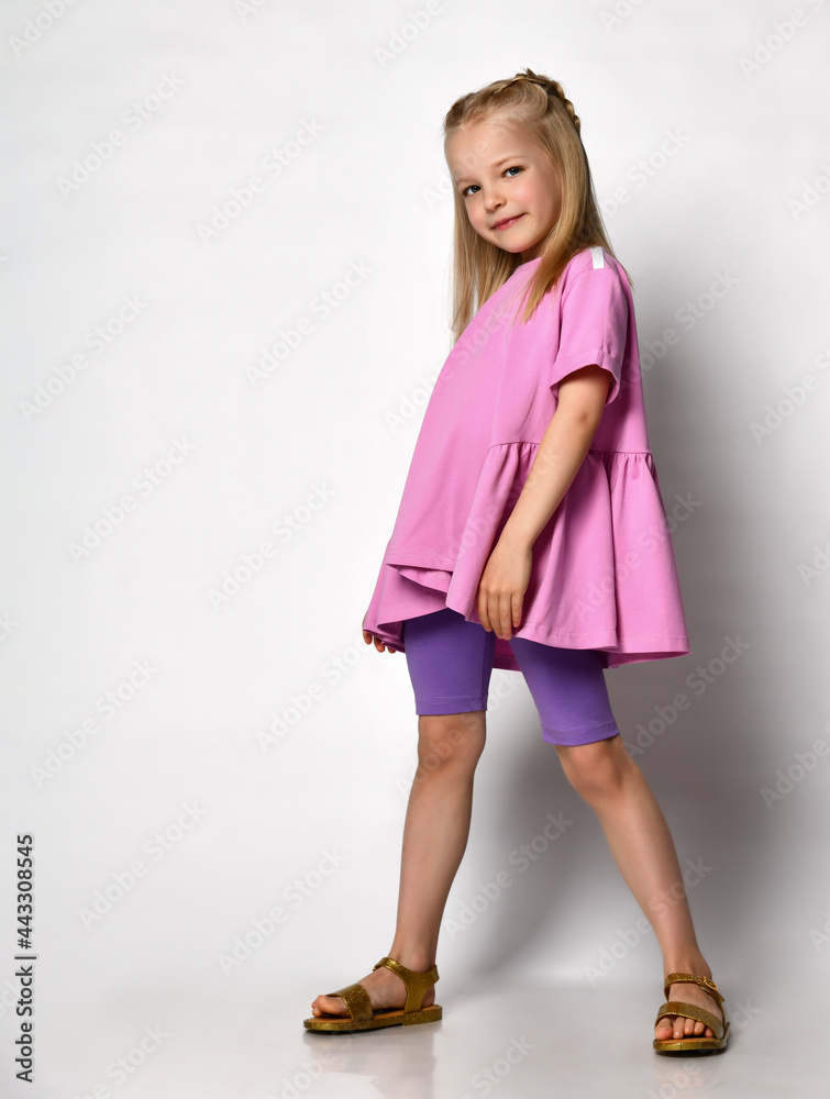 Cute little girl standing in a blouse with a fuchsia peplum and legends on a light background in the studio. Summer concept, fun and relaxation, posing on light background Cute little girl standing in a blouse with a fuchsia peplum and legends on a light background in the studio. Summer concept, fun and relaxation, posing on light background