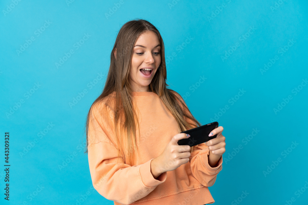 Young Lithuanian woman isolated on blue background playing with the mobile phone Young Lithuanian woman isolated on blue background playing with the mobile phone