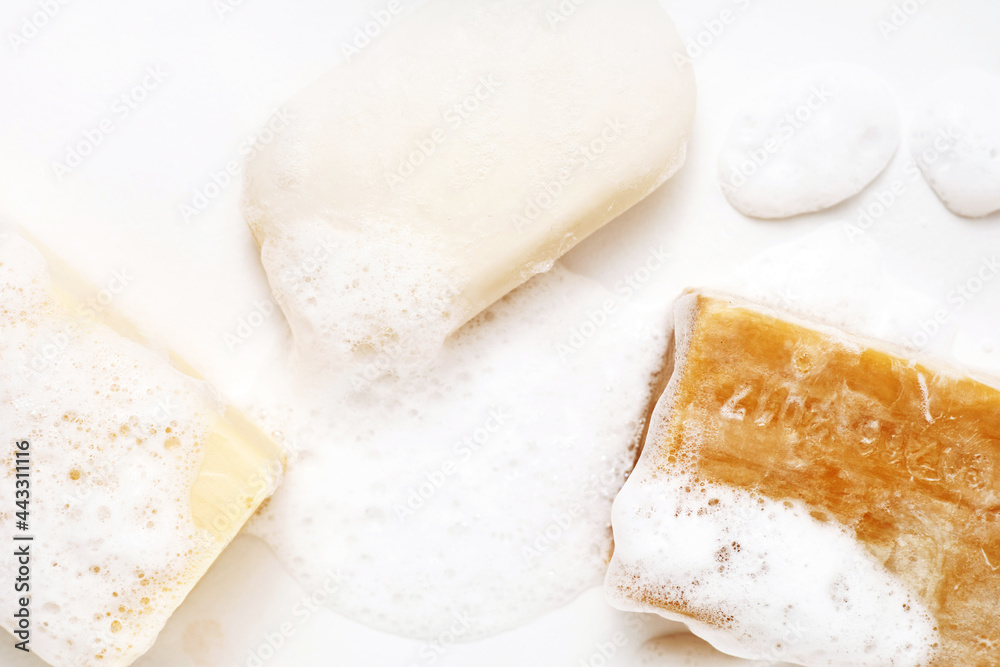 Soap bar and foam on white background, top view. Hygiene concept