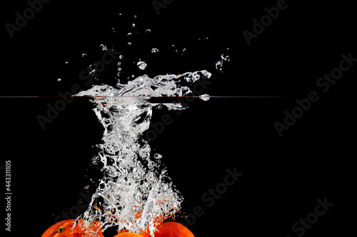 tangerines fall into the water, place under the text, black background, isolate