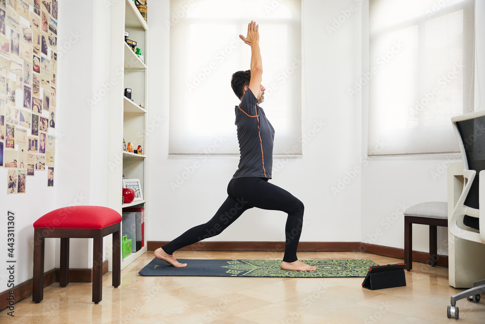 young middle aged man doing yoga and stretching at home