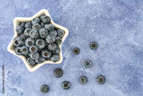Blueberries for the 4th of July, blueberries in heart shaped bowl, against a blue background 