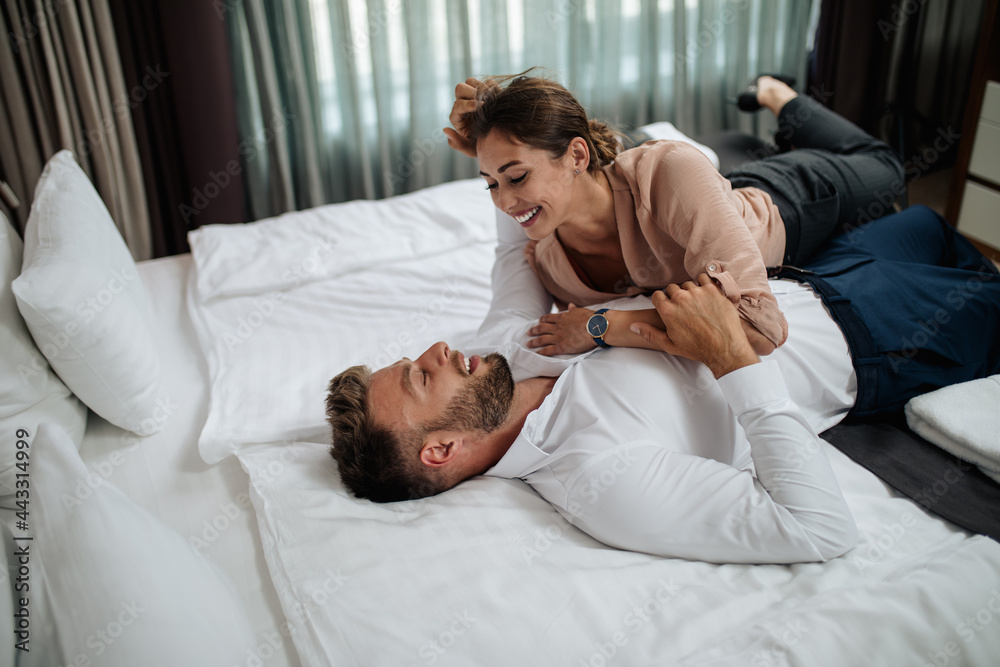 Happy couple flirting and enjoying together on a comfortable bed at hotel room. Happy couple flirting and enjoying together on a comfortable bed at hotel room.