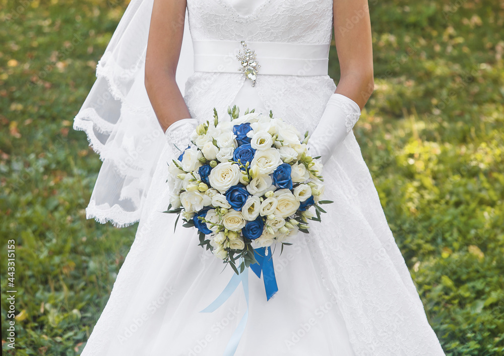 Bride in white wedding dress holds a bouquet of flowers white and blue roses close up Bride in white wedding dress holds a bouquet of flowers white and blue roses close up