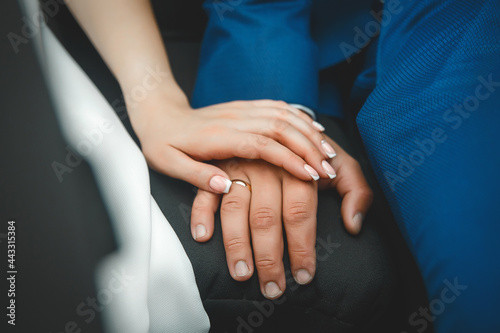 The hand of the young bride lies on the hand of the groom at the wedding, close-up