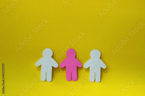 Paper cut pink human between two white paper people shapes. Three figures. Social interaction concept. Team work. Diversity.