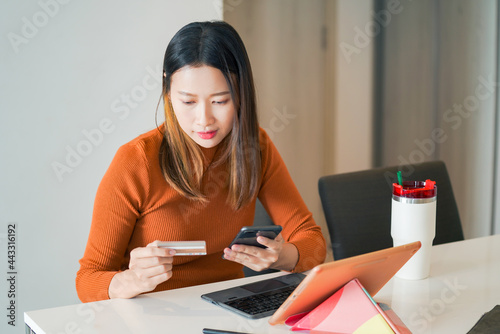 Asian woman using smartphone with credit or debit card for online shopping at home. Happy female shopper enjoy purchase goods in online store with easy e-banking online payment on mobile application